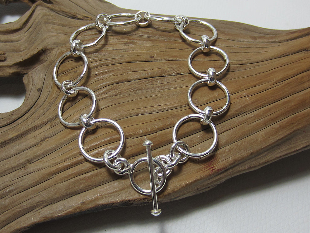Simple but effective sterling silver bracelet made up of 15mm diameter circle links. It is 19cms long including the t-bar fastener. It weighs around 13.5 grams and carries a full set of UK Hallmarks. 925 Silver Canterbury