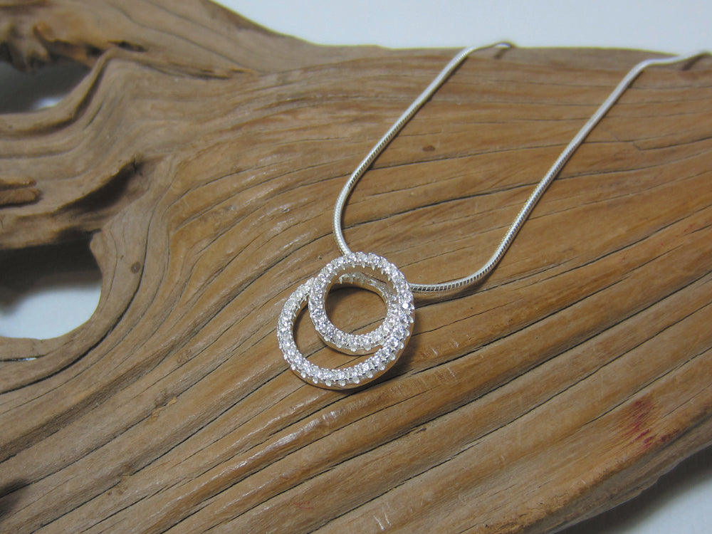 Spiral sterling silver pendant pendant set with cubic zirconia stones giving a real sparkle. It measures 16mm across and is shown here on a fine snake chain. 925 Canterbury