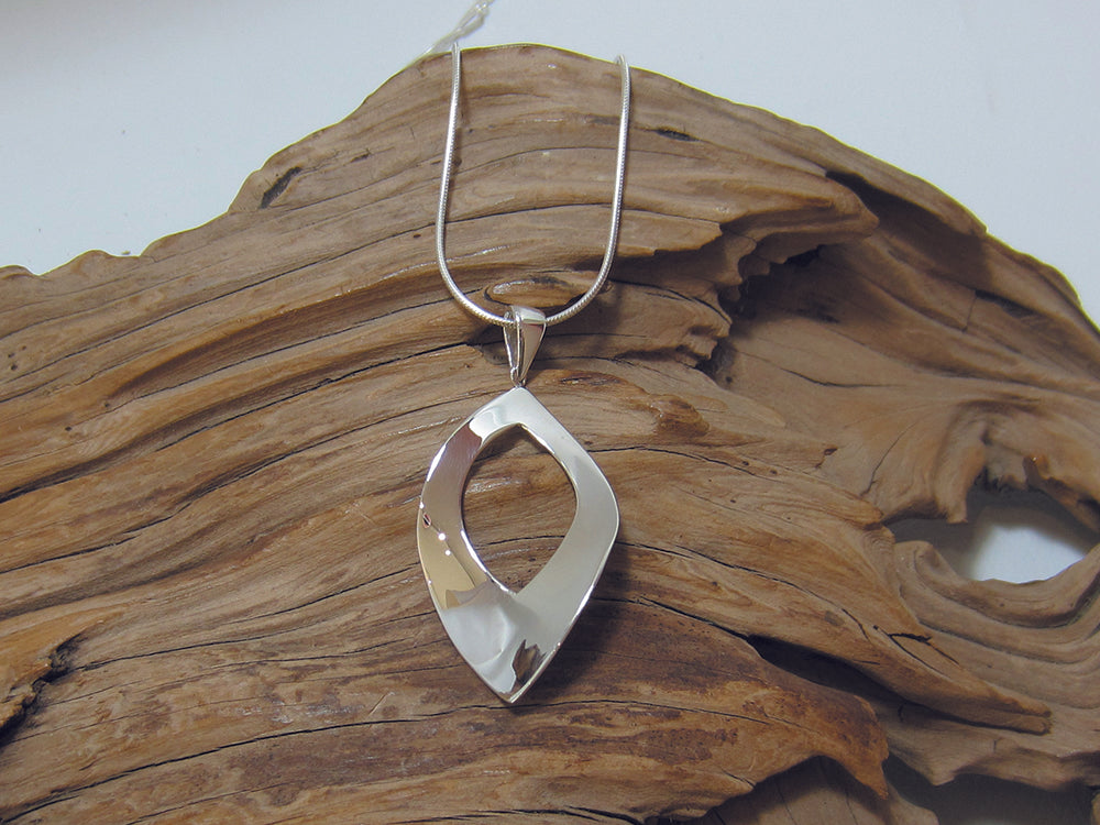 A simple, sterling silver, curvy leaf shape with cut-out centre. It is 40mm long and is shown here on a fine snake chain. 925 Silver, Canterbury