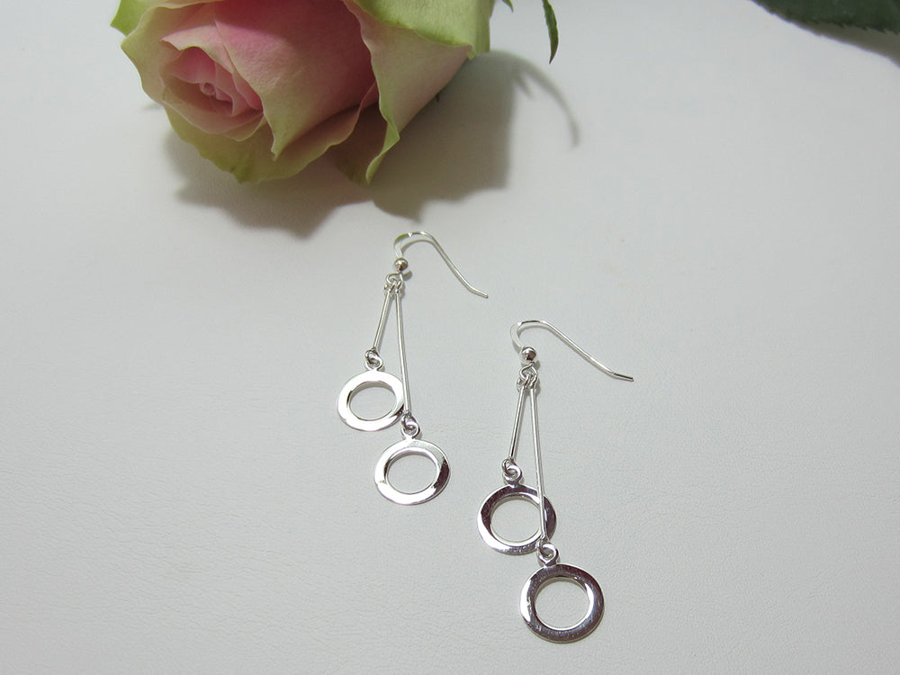 A double bar sterling silver drop earring with an 11mm diameter circle at the bottom of each stem. They are 45mm long at the longest point. 925 silver Canterbury