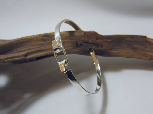 The belt buckle style clasp allows the bangle to open so it easily slips over the hand. The bangle sterling silver measures 65mm across at it's widest point and is 5mm deep, it weighs 16.6 grams and carried a full set of UK Hallmarks. 925 Silver, Canterbury