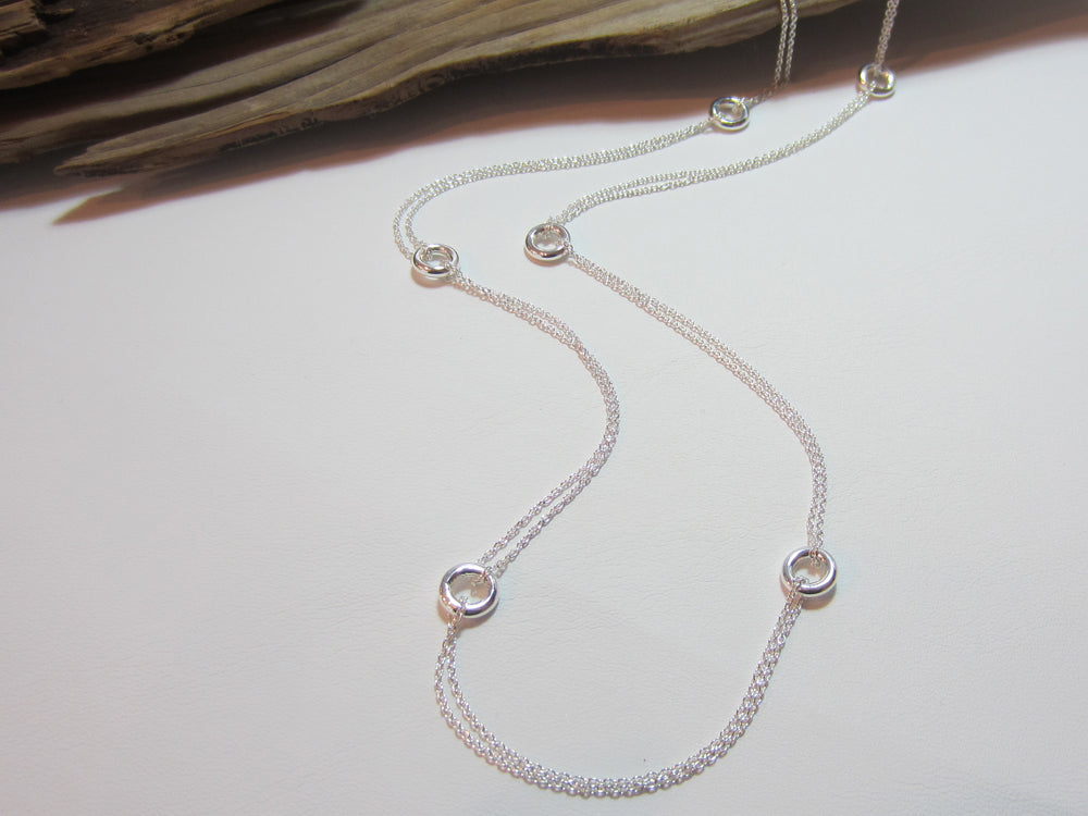 This sterling silver necklace measures 80cm or 32" long. It is made up of 8mm doughnut shpaed beads linked by a double length of fine trace chain. 925 Silver Canterbury