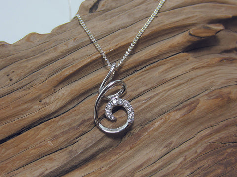 Interesting swirly design with cubic zirconias set into the final curl of this sterling silver pendant. It is 22mm long and 13mm wide. It is rhodium plated for extra sparkle and is shown here in a medium curb chain. 925 Canterbury