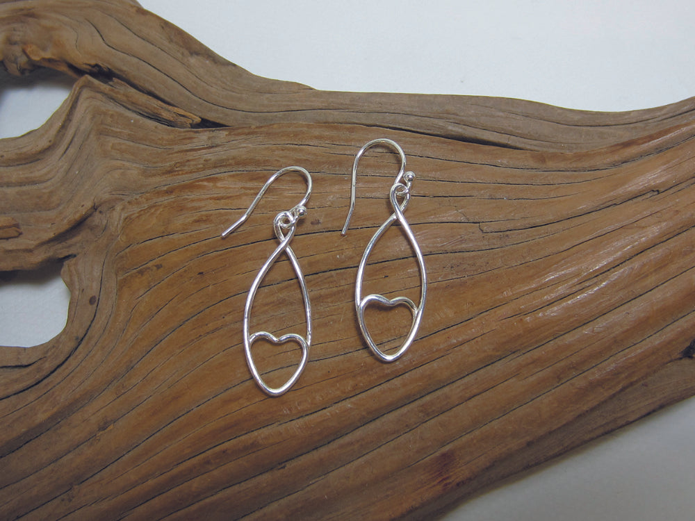 A single sterling silver wire winds round creating a discrete heart shape. The earrings are 30mm long and 10mm wide. 925 Canterbury