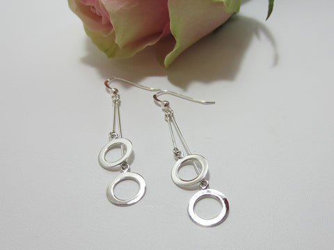 A double bar sterling silver drop earring with an 11mm diameter circle at the bottom of each stem. They are 45mm long at the longest point. 925 silver Canterbury
